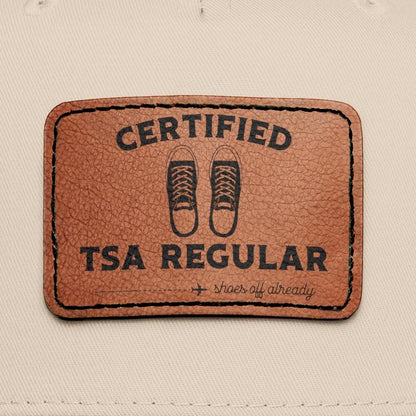 Beige and black cap with a brown leather patch featuring 'Certified TSA Regular (shoes already off)'