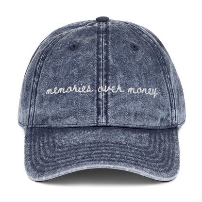Vintage navy travel themed hat with the words "memories over money" embroidered on it
